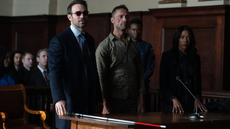 Charlie Cox as Matt Murdock, Kamar de los Reyes as Hector Ayala, and Niki M. James as Kirsten McDuffie standing in court in Daredevil: Born Again