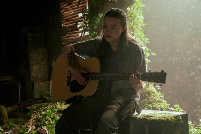Bella Ramsey as Ellie in 'The Last of Us' Season 2, Episode 4, shown playing guitar with sunlight behind her