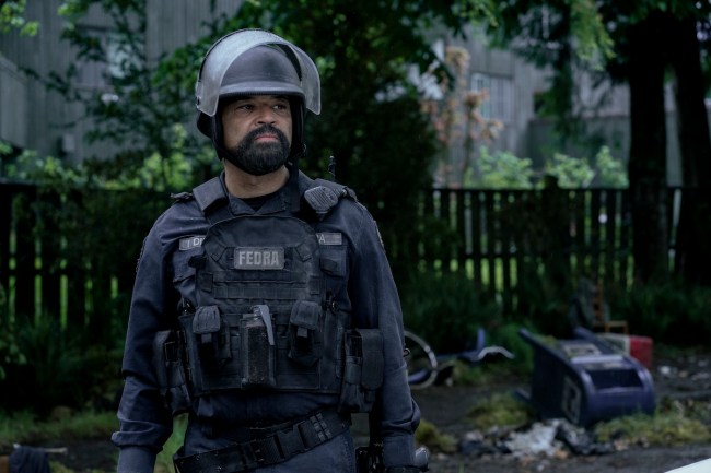 Jeffrey Wright in 'The Last of Us' Season 2, Episode 4, shown here wearing FEDRA riot gear, standing outside near a neighborhood fence