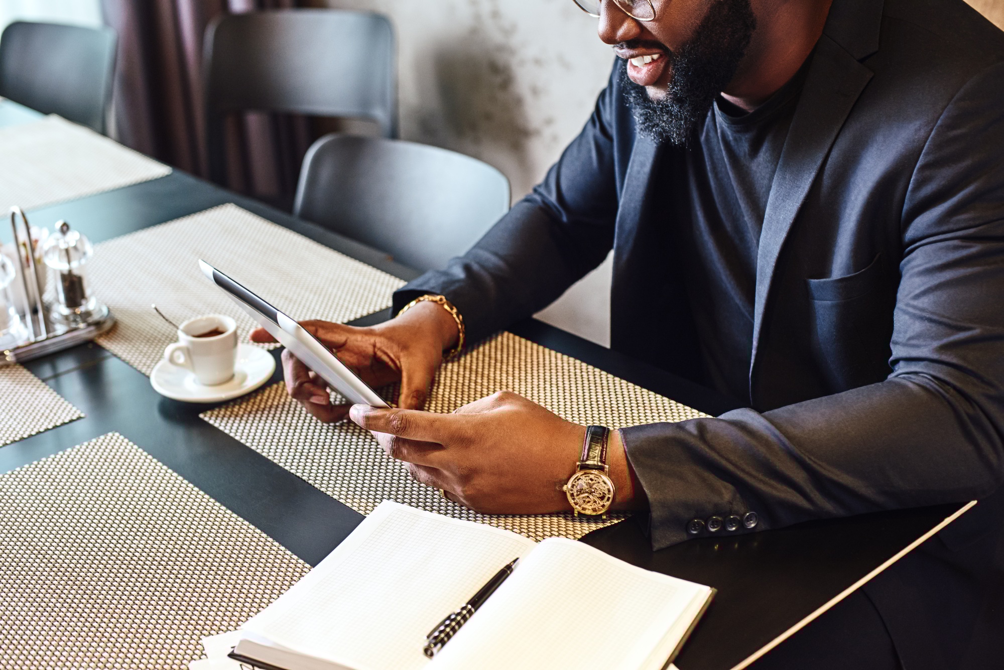 Cropped image of a young afro american businessman using tablet while resting in the cafe