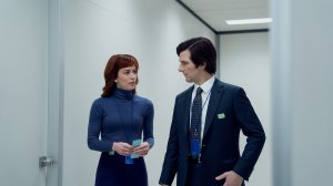 Britt Lower and Adam Scott in 'Severance' Season 2 Episode 10, shown here walking down Lumon's white hallways, wearing work attire