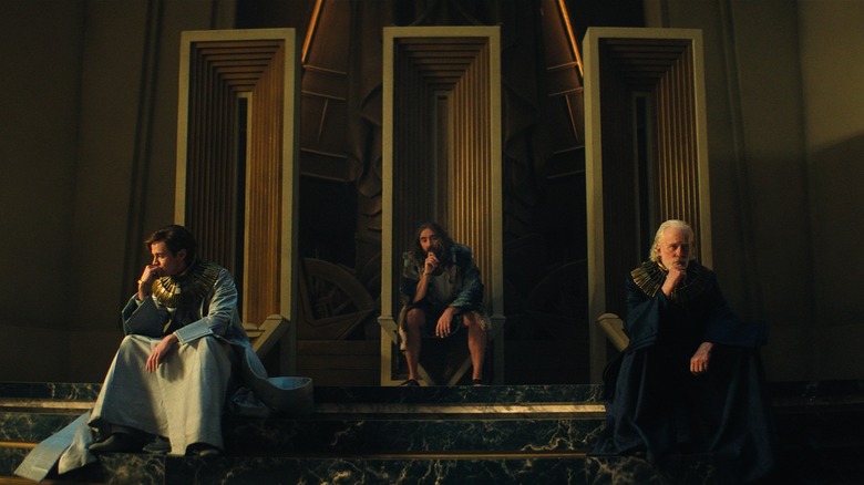 The three Cleons sit on their thrones with their hand on their chin in Foundation