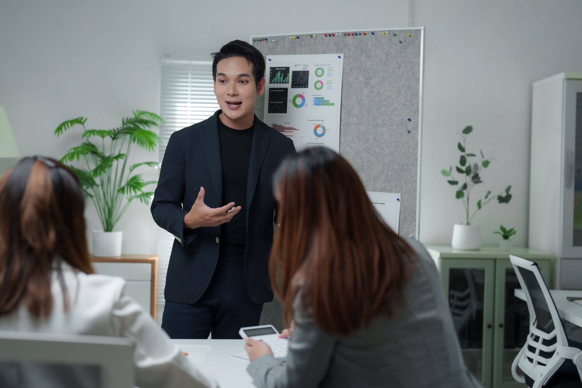 Asian businessman leading meeting with charts on board