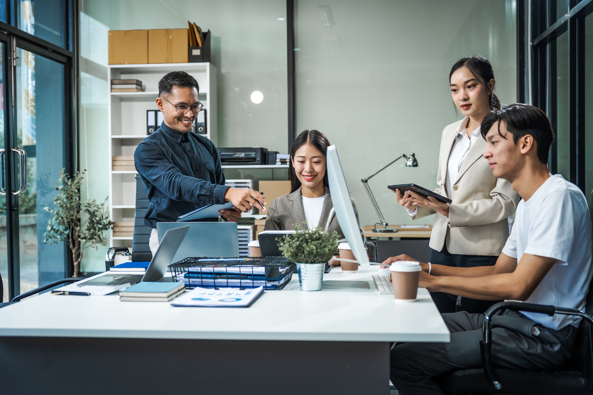 Asian colleagues meet at a desk, discussing business financial terms, investment strategies