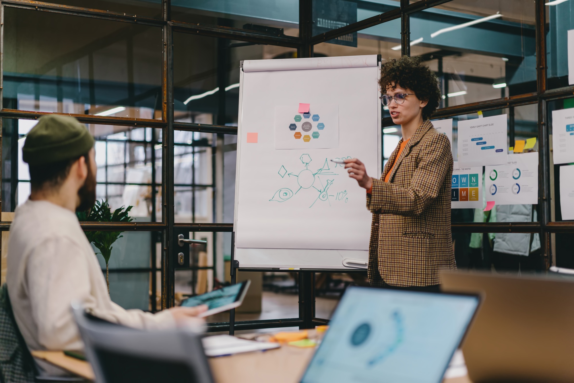 Focused young woman explaining project with chart on board to colleague
