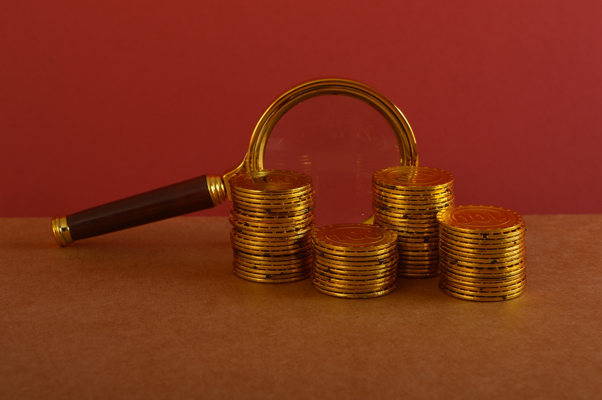 Magnifying glass and golden coins. Inflation, cash flow, tax and financial concept