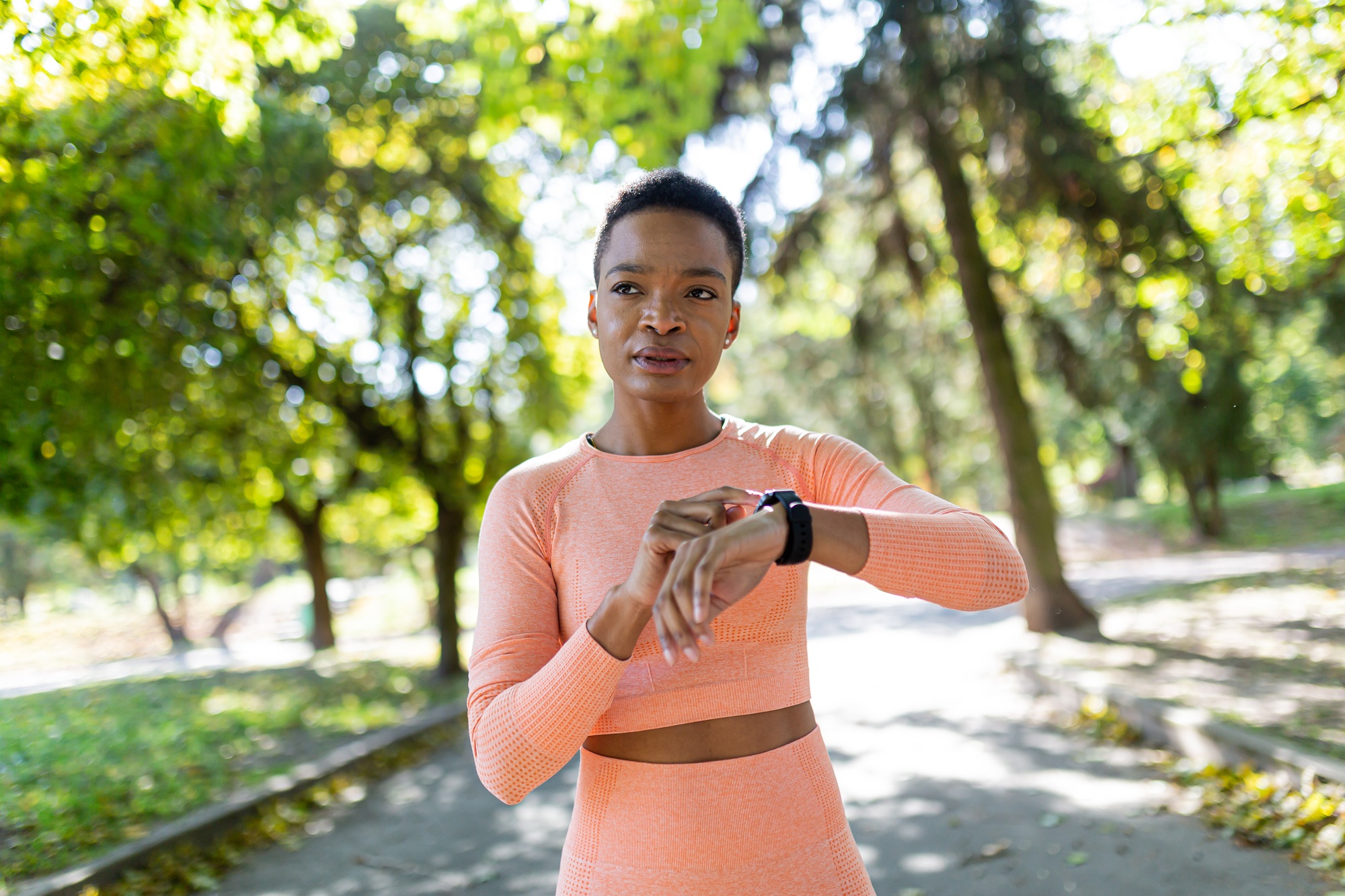 Afro american female athlete before training chooses fitness program on a bracelet