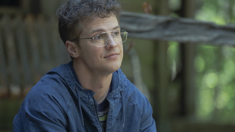 Vigilante sitting outside a cabin looking wistful in Peacemaker season 2