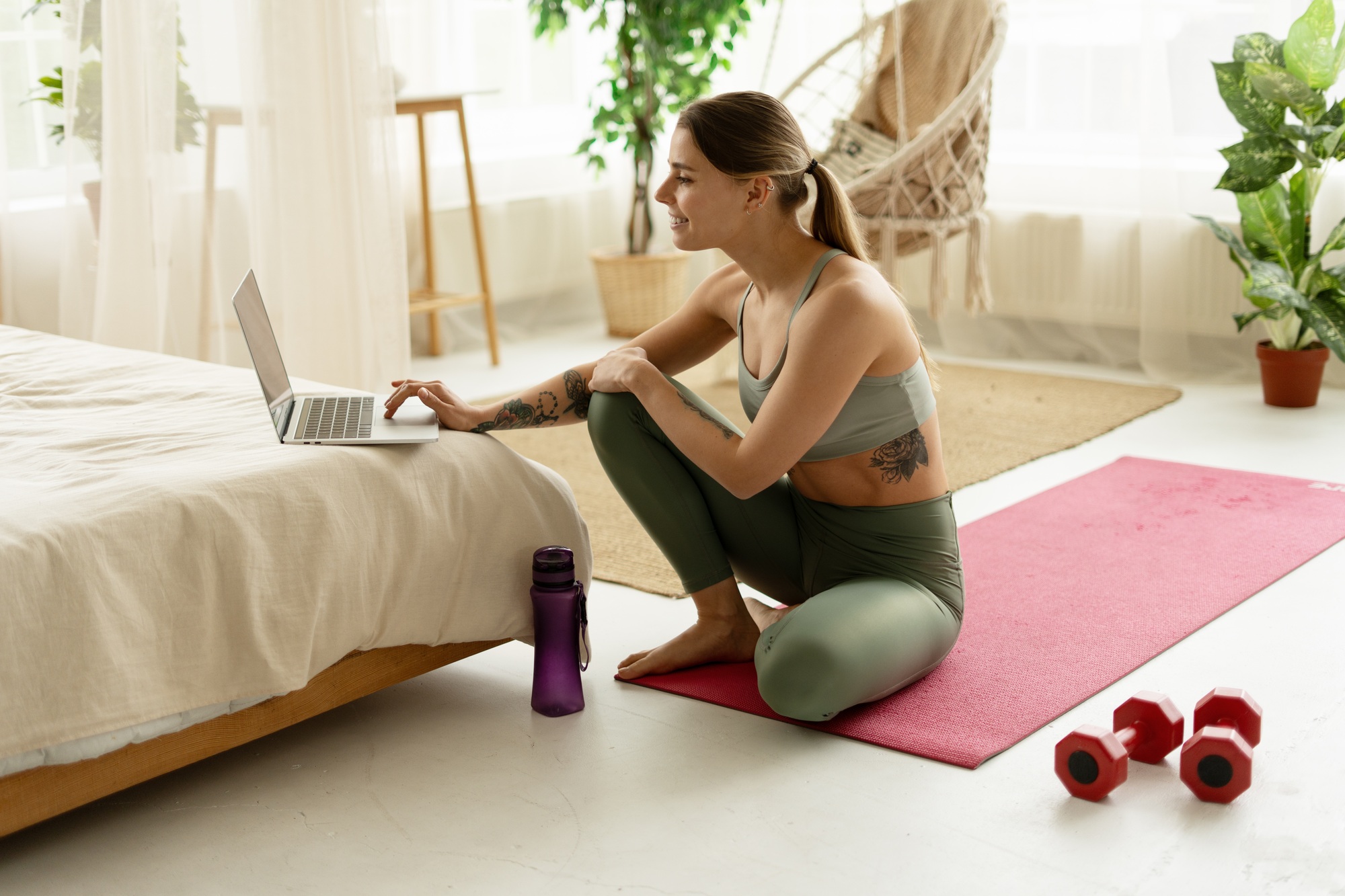Young woman choosing online training program on laptop in bedroom