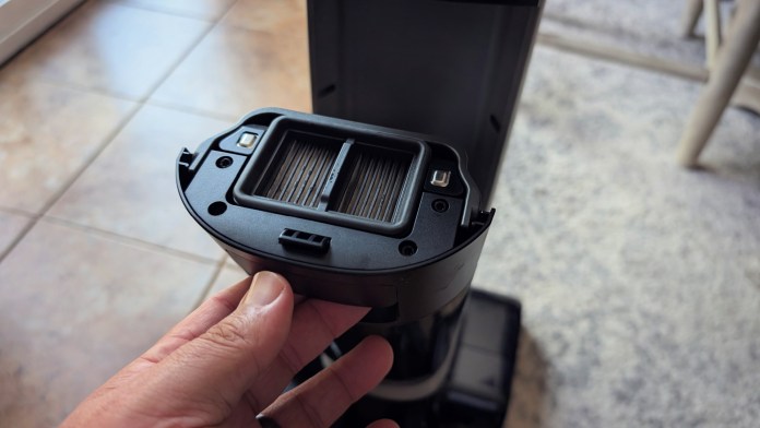 Close-up view of a hand holding a vacuum filter component, highlighting its design and features.