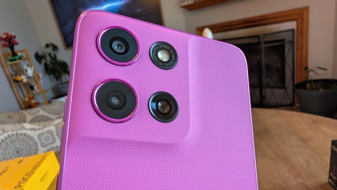 Close-up of a pink smartphone showing three camera lenses on the back.
