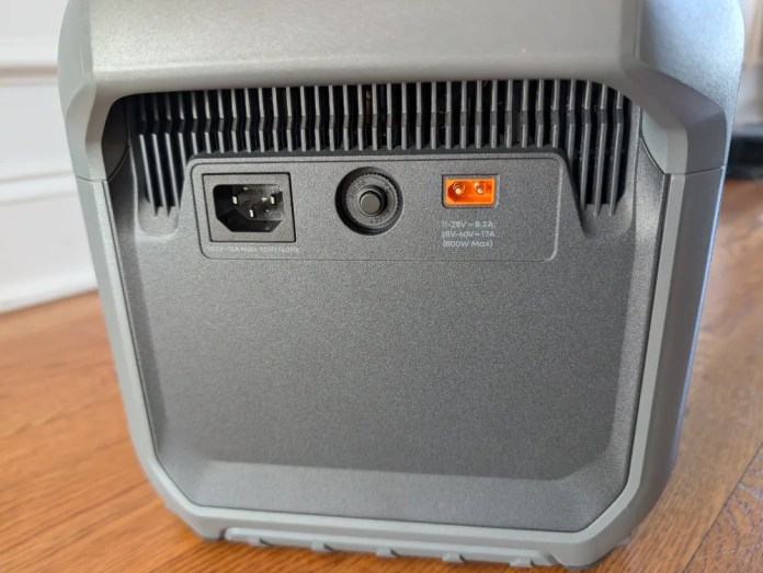 Rear view of a device showing power and charging ports on a gray exterior with ventilation grilles.